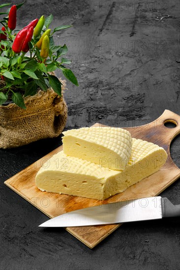 Fresh Adyghe cheese cut on slices on wooden cutting board