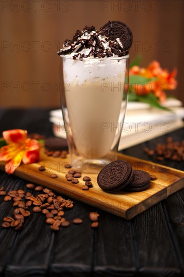 Glass with coffee cocktail with whipped cream and cookie decorated with coffee beans and flowers