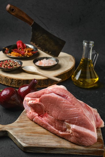 Raw slice of beef steamship round with cooking ingredients on black background