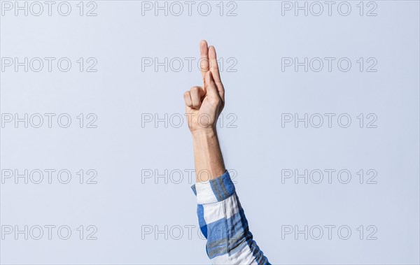 Hand gesturing the letter U in sign language on an isolated background. Man's hand gesturing the letter U of the alphabet isolated. Letter U of the alphabet in sign language