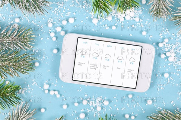 Concept for cold winter temperatures with snow showing mobile phone with weather forecast