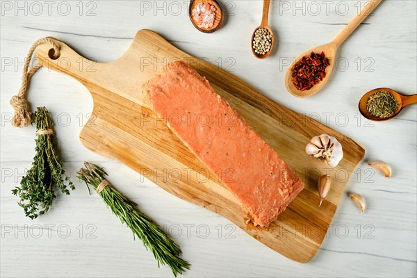 Overhead view of raw pieces of salmon pressed in briquette with spice and herbs