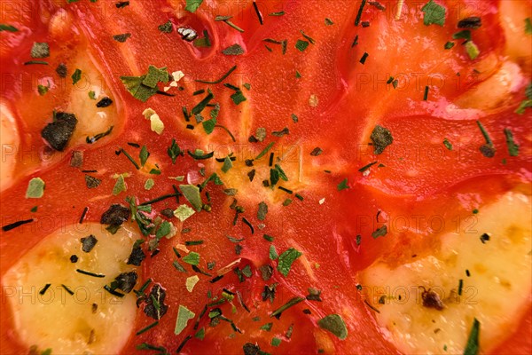 Macro photo of tomato with dry herbs on pizza