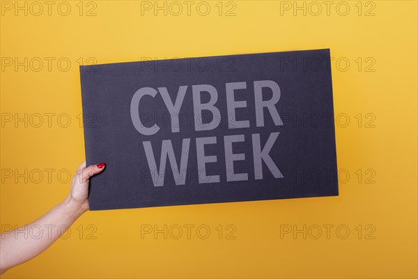 Female hand holding a cyber week poster. Studio shot