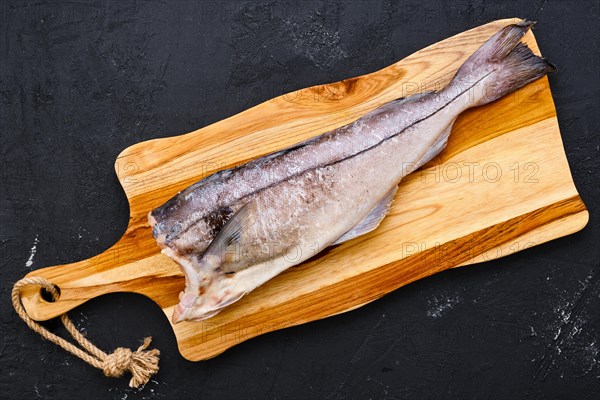 Top view of raw fresh haddock carcass on wooden cutting board