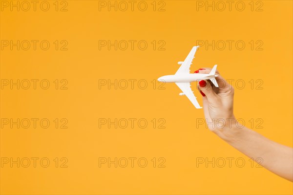 Front view hand holding plane figurine with copy space