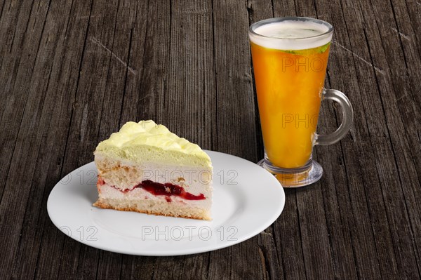 Cherry cake with whipped cream and glass of sea buckthorn tea on wooden table