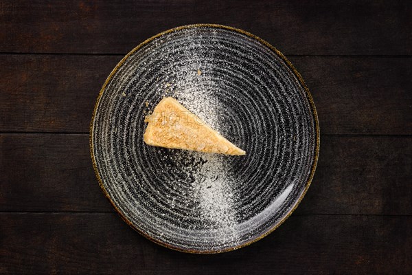 Top view of plate with piece of coconut cake on wooden background
