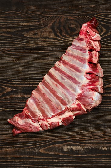 Overhead view of raw fresh deer ribs over dark wooden background