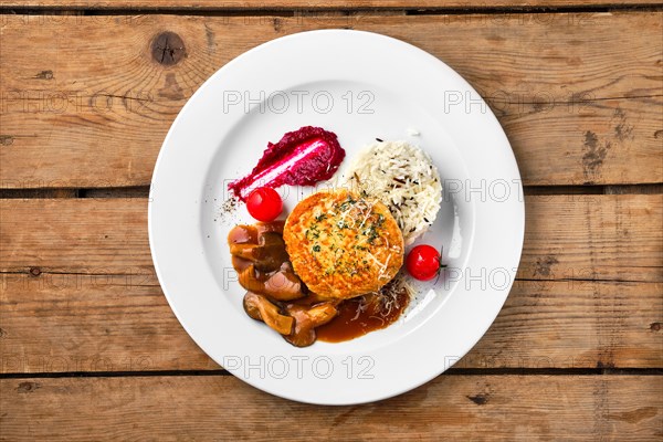 Top view of beef cutlet with rice and mushroom sauce on rustic table