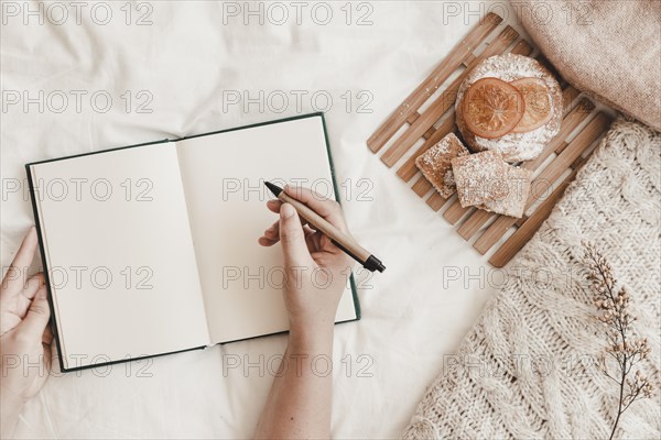 Hand holding pen with opened notebook bed