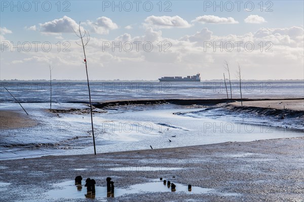 Tidal creek am Wadden Sea mit Containerschiff in der Wesermuendung