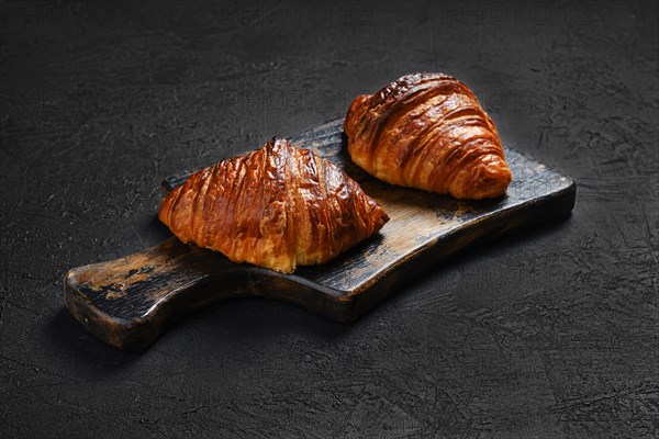 Crispy croissant on wooden serving board