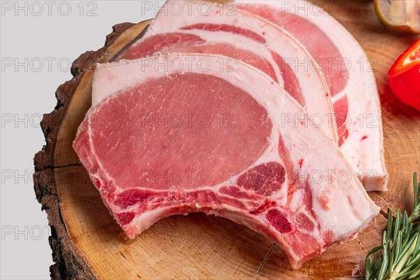 Raw fresh pork fillet steak on the bone on wooden cutting board