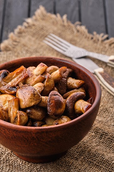 Clay plate with roasted mushrooms on dark wooden table