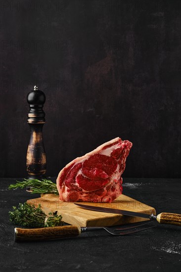 Raw strip steak bone in on dark background