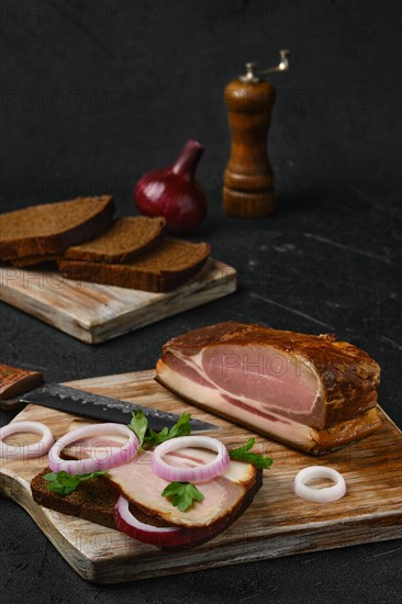 Rural sandwich with smoked bacon with brown bread on wooden cutting board