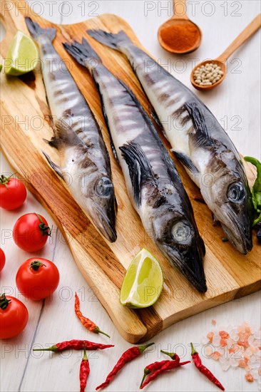 Raw fresh icefish on wooden cutting board with spice and herbs