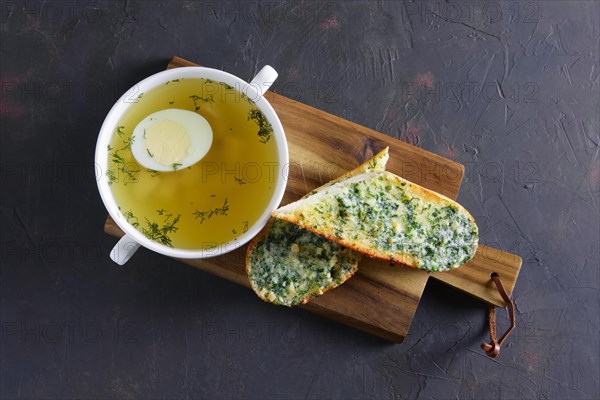 Clear chicken broth with egg served with toasts