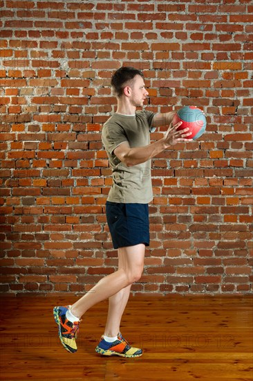 Athletic man doing balance exercises with ball. Fitness workout