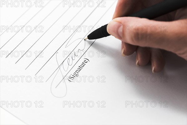 Hand signing document with pen