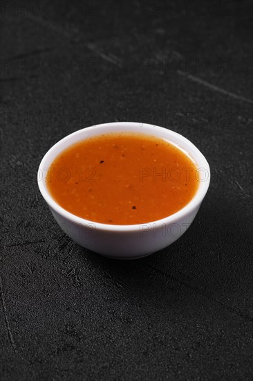 Small bowl with spicy orange sauce for poultry