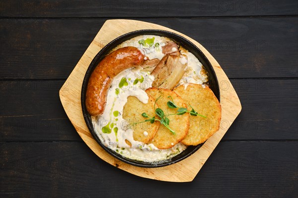 Top view of potato fritters with with fried german sausage and pork belly slices