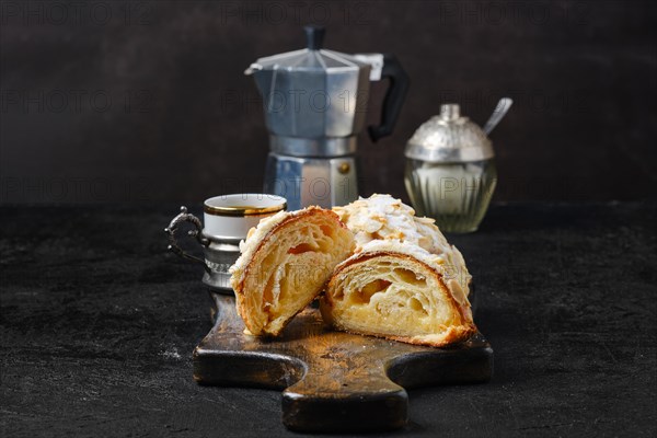 Fresh croissant with caramel filling cut on half with cup of espresso