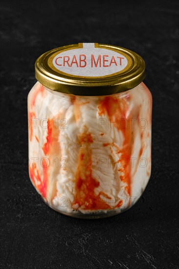 Canned crab in glass pot on black background