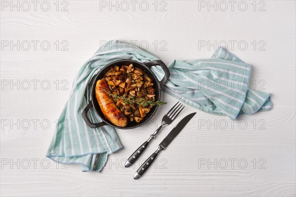 Cast-iron pan with fried sausage and mushrooms