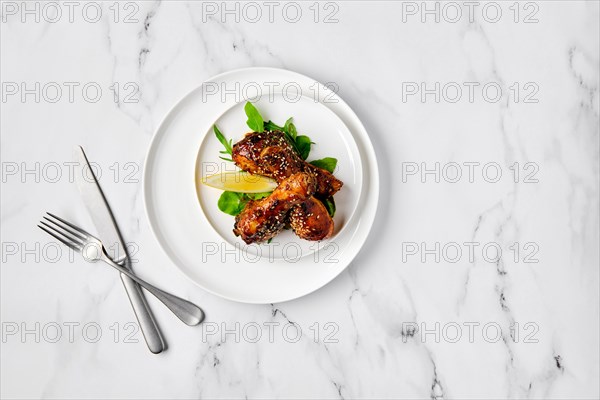 Overhead view of baked chicken legs with spicy sauce on a plate