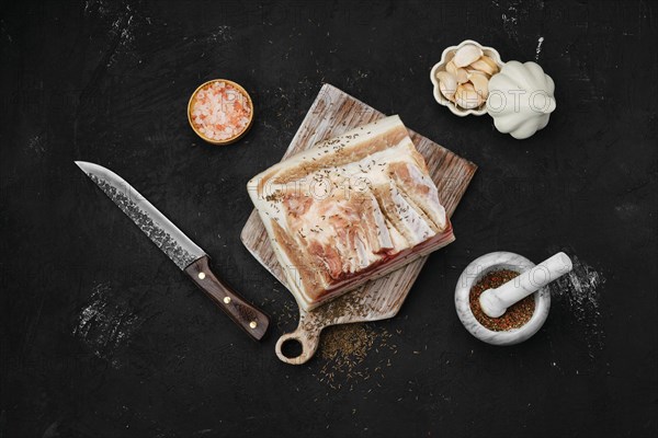 Overhead view of salted with caraway pork belly lard on cutting board