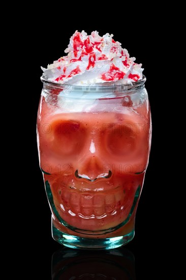 Halloween strawberry cocktail with whipped cream in skull glass isolated on black