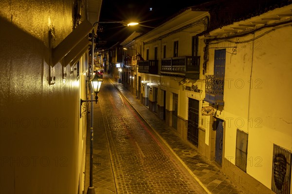 View from hotel balcony of cobblestone alley at night