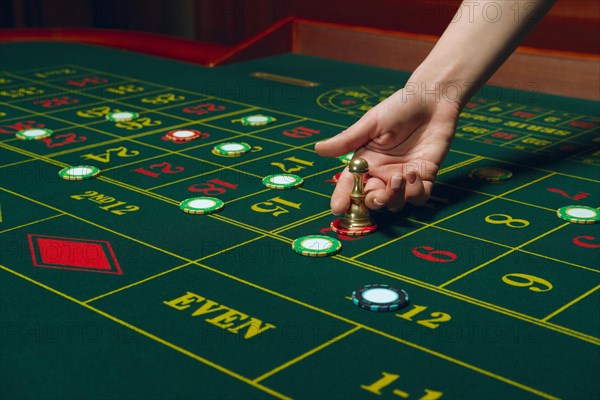 Casino roulette table with chips and cards. Winning combination. Hand of Croupier behind gambling table