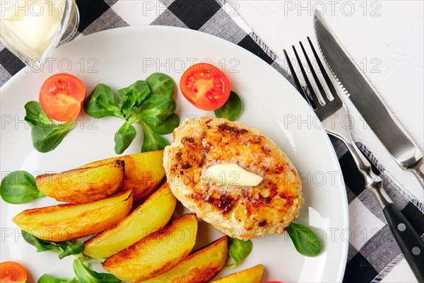 Fried chicken cutlet with potato slices served with tomato cherry and corn salad. Traditional belorussian food