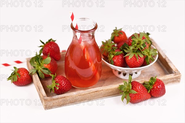 Healthy strawberry fruit lemonade in jar surrounded by berries on wooden tray