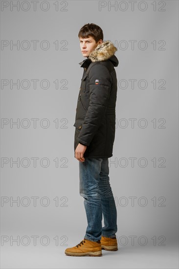 Full length portrait of handsome man in warm winter coat posing in studio