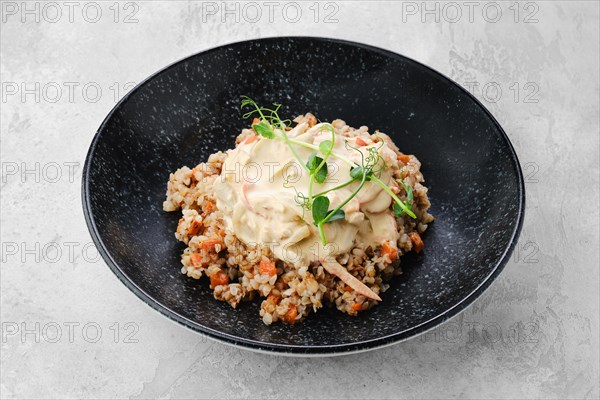 Buckwheat porridge with slices of fried carrot and creamy flour sauce on a plate