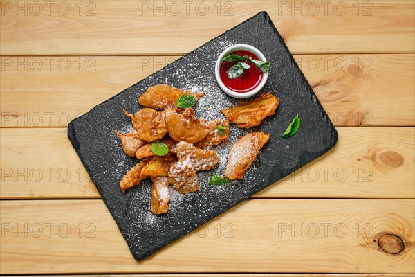 Overhead view of deep fried fruits in breading served with caramel and strawberry jam