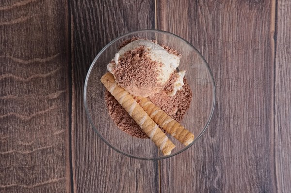 Ice cream with chocolate and cookie in glass on wooden table. Top view