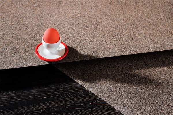 Egg cup with brown egg on abstract background and long shadow