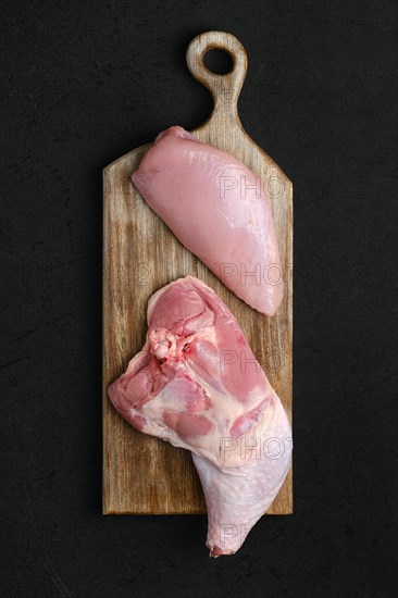 Overhead view of raw turkey leg amd breast fillet on cutting board