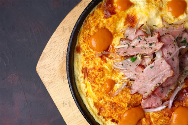 Omelette with bacon and fried onion on cast-iron pan