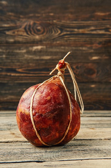 Round fermented beef sausage on wooden table