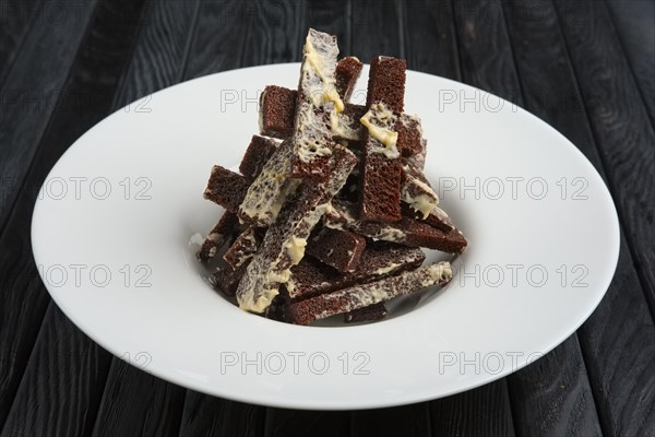 Fried brown bread sticks with melted cheese on a plate