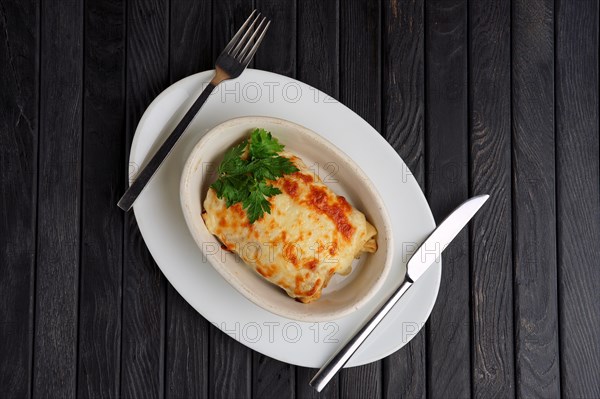 Top view of deep plate with pancakes covered with melted cheese