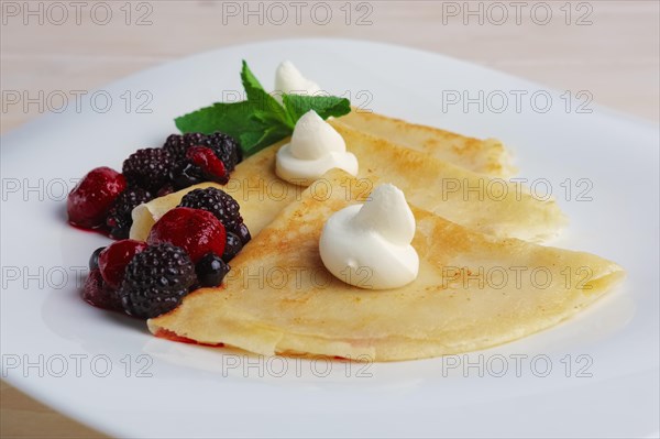 Portion on thin pancakes with sweet cream cheese and berries