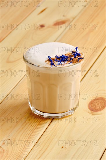 Flat white coffee in transparent glass on wooden background
