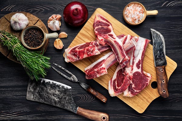 Overhead view of raw fresh lamb rack with spice on a wooden board